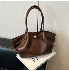 Macro shot of brown leather tote bag with pleated side details and golden buckle