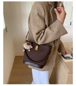 Detail of coffee leather bucket bag with gold hardware and a cute white sheep charm accessory