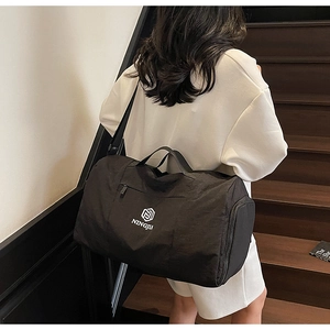 Detail view of black waterproof travel duffel with adjustable shoulder straps on stairs