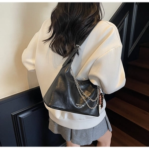 Detail of black leather underarm bag with silver chain strap and New York print