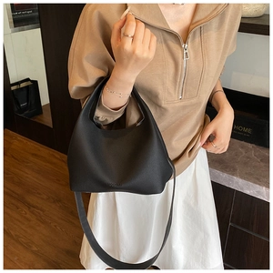 Detail of black lychee texture bucket bag with embossed logo and detachable shoulder strap