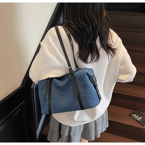 Vista posteriore di una modella con la borsa tote in denim blu, cinturini in pelle e cerniera