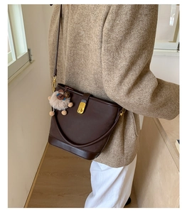 Dettaglio borsa a secchiello vintage marrone con fibbia dorata e ciondolo a pecora