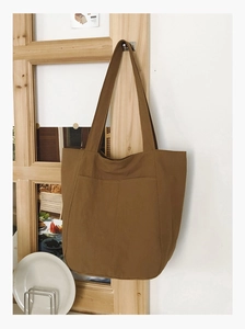 Detail of caramel canvas tote bag showing front pockets and minimalist casual design