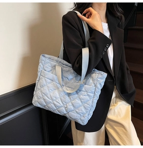 Close-up of a light blue quilted tote bag with diamond stitching shown on a model