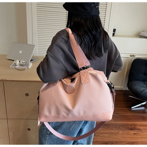 Detailed view of pink travel bag with woven texture and reinforced shoulder strap