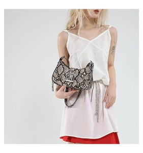 Detail view of snakeskin textured handbag with metallic buckle and punk style rivets