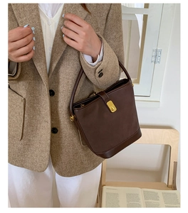 Dettaglio borsa a secchiello vintage in pelle marrone con chiusura dorata e manico