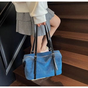 Dettaglio della grande borsa tote in denim con cinturini in pelle nera e fibbie d'argento