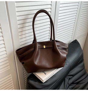 Detail of dark brown tote bag featuring lychee texture leather and gold square metal clasp