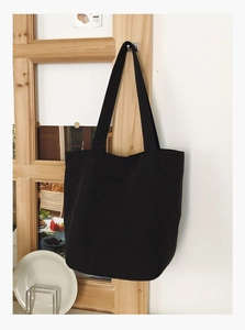 Detail of a large black canvas tote bag hanging on a door for a casual daily lifestyle view