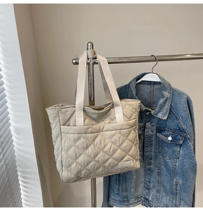 Detail of beige quilted tote bag showing rhombus stitching and a front pocket