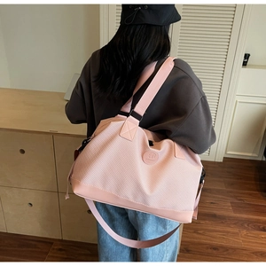 Pink travel bag with woven texture detail showing sturdy carrying handles and logo patch