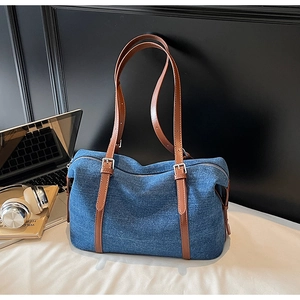 Dettaglio della borsa tote in denim blu con manici in pelle marrone e fibbie d'argento
