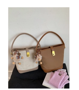 Close-up of matte leather bucket bags with metal turn-lock and plush sheep charm detail