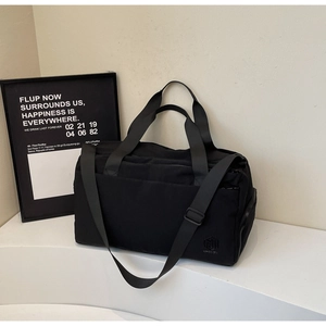 Close-up of minimalist black travel bag featuring high-density fabric and side zipper pocket