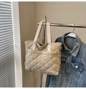 Detail of beige quilted tote bag showing textured diamond pattern and NingJia brand tag