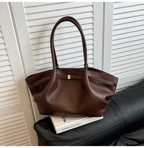Macro detail of dark brown lychee leather tote with pleated texture and gold metal buckle