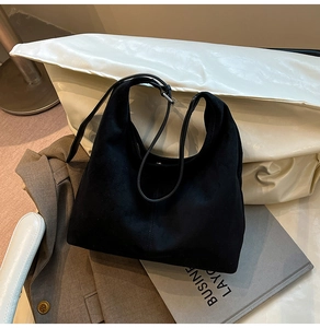 Detail of black suede hobo bag with stitching and leather strap on business attire