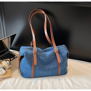 Dettaglio della borsa tote in denim blu con manici in pelle su una scrivania