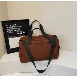Detail view of large brown duffel bag with black straps on a modern geometric setup