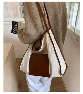 Detail of canvas tote bag with contrast leather pocket and long shoulder straps