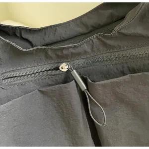 Detailed close-up of smooth metal zipper and nylon texture on a large black tote bag