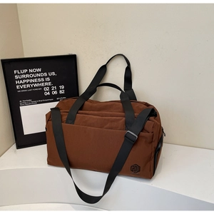 Detail of a brown large-capacity duffel bag with black straps on a minimal stand