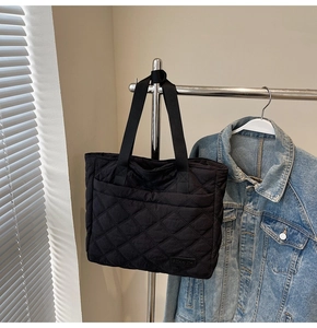 Close-up of a black quilted tote bag with diamond pattern hanging on a hanger
