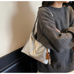 Silver metallic underarm bag featuring double metal chains and wooden bead tassel detail