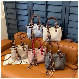 Detail view of stylish drawstring bucket bags in five retro colors on a leather bench