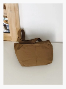Detail of a khaki tote bag with reinforced stitching and wide shoulder strap