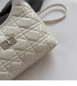 Close-up of beige quilted shoulder bag with silver turn-lock and soft texture detail