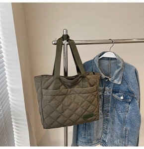 Detailed view of olive green quilted tote bag featuring a front pocket and brand label