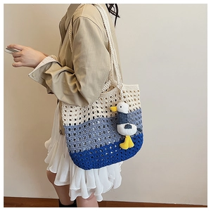 Detail of three-tone gradient woven tote bag with a small seagull plush pendant detail