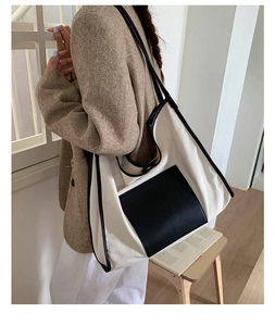 Detail of high-capacity canvas tote bag with black leather trim and shoulder straps