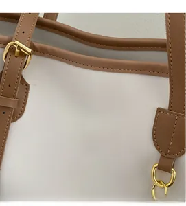 Close-up of contrast stitch PU leather trim and gold metal buckle on a large tote bag