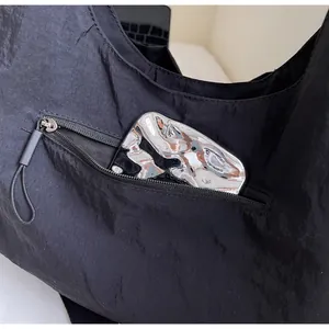 Detail of exterior side zipper pocket on a black nylon tote bag showing storage space