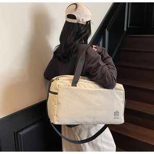 Detail of light beige travel bag featuring durable nylon texture and adjustable black strap