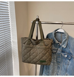 Detail of olive green quilted tote bag hanging with brand label on nylon fabric