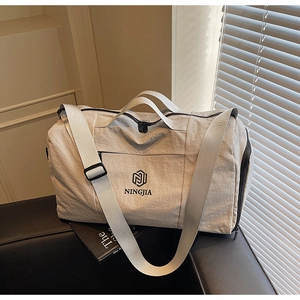Detail of a beige nylon travel bag showing a durable handle and black logo on a leather seat
