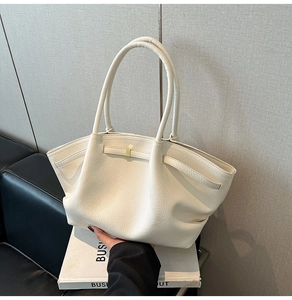 Close-up of cream white lychee textured tote bag with gold buckle and pleated detail