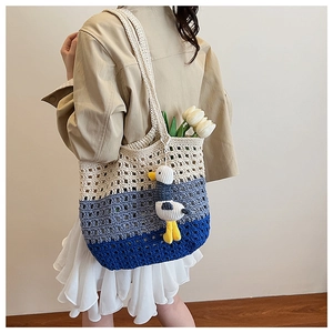 Detail of hand-crocheted gradient tote bag with cute duck charm on model's shoulder