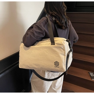 Side view of cream travel bag showing high-capacity zipper pocket and adjustable strap