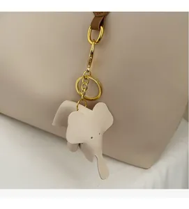 Detailed close-up of a cream elephant leather bag charm with gold metal hardware