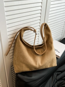 Minimalist camel suede hobo tote bag with large capacity on a leather sofa