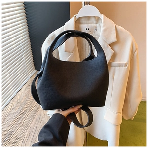 Detail of black lychee grain leather bucket bag with wide integrated handle texture