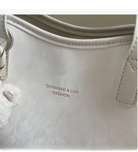 Detail der weißen PU-Leder-Einkaufstasche mit Marmortextur, Bärenanhänger und Logo
