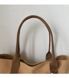 Close-up of durable brown canvas tote bag with reinforced handles and brand tag