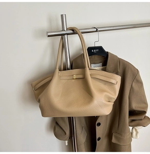 Close-up of beige lychee grain leather tote bag with side belt and gold hardware